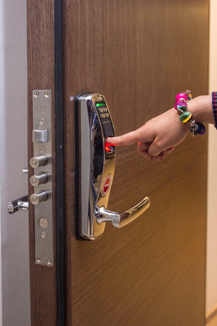 A hand using fingerprint access on a digital security door lock, enhancing safety.